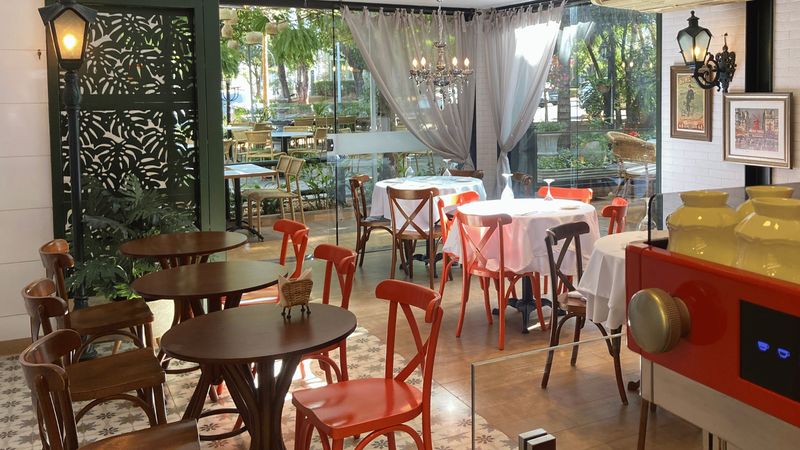 Salão do Café Angelita com mesas de madeira e cadeiras vermelhas